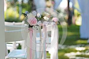 Tenderless boutonnieres on wedding chairs on each side of archway photo