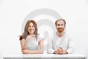 Tenderless funny redhead girl and boy sitting at white desk