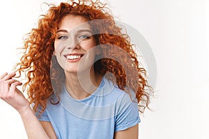Tenderness, beauty, haircare concept. Alluring sensual young woman with natural curly red hair, rolling strand on finger