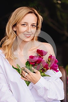 tenderness. a blonde woman in a white shirt and a bouquet of peonies.