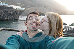 Tenderness Friends kissing in the check and hugging in the coast pool. Caucasian wife with glasses giving kiss to handsome latin