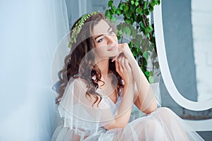 Tenderness and sensuality concept. Beautiful brunette model posing on bed in white lingerie. Sensual portrait of young