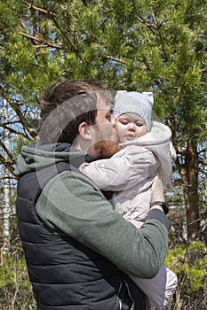 Tenderness taking care of children love dad and daughter, the young man holds in his arms kisses baby girl in swarm suit