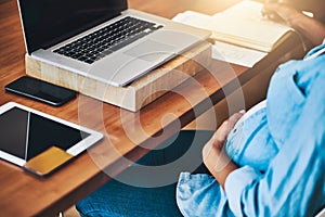 Tending to business before baby arrives. a pregnant woman using a laptop while working from home.