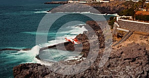 TENERIFE, CANARY ISLANDS, SPAIN, 2023 April: Medical helicopter landing on rocky volcanic shore for rescue operation at