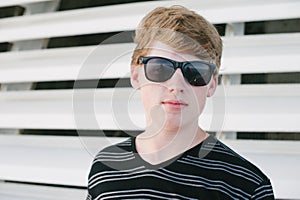 Tenn boy in striped shirt and sunglasses.