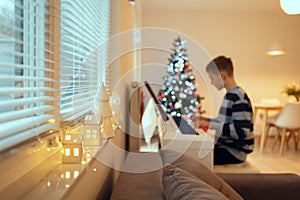 Tennage boy practise plaing piano with new years tree on background