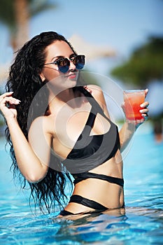 Tenned beautiful woman in black bikini and sunlasses sitting in