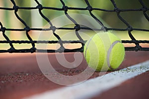 Tennis ball in the black net on hard tennis court surface