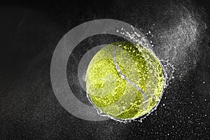 Tennis ball flying in water drops and splashes isolated on black background