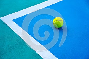 Tennis ball on hard modern blue court near white line