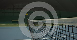 Tennis ball hitting into the net at high speed on the blue court. Sport training, sport concept. Hitting a small ball in