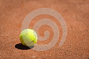 Tennis ball lying on orange sand