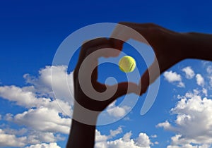 Tennis ball midair with cloudy sky above