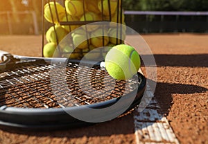 Tennis ball, racket and basket on clay court, closeup