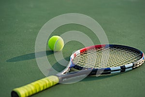 Tennis ball and racket under late evening sunlight