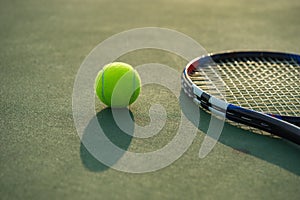 Tennis ball and racket under late evening sunlight