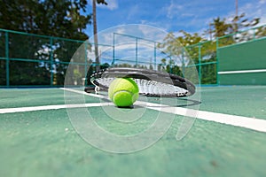 Tennis ball and racquet on court