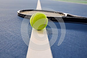 Tennis ball and racquet on a court line