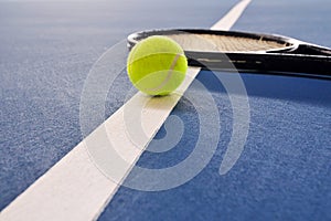 Tennis ball and racquet on a court line