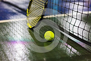 Tennis ball, racquet and net on wet ground after raining