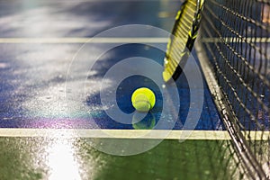 Tennis ball, racquet and net on wet ground after raining