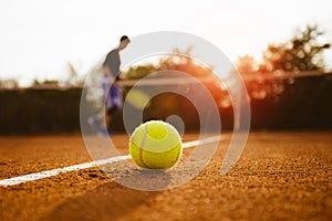 Tennis ball and silhouette of player on a clay court