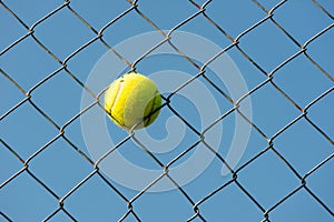 Tennis ball stuck in steal wire net horizontal shot