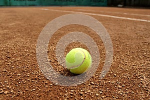 Tennis ball on a tennis clay court. Red clay tennis court. Sand on a tennis court. Close up of tennis ball on clay court