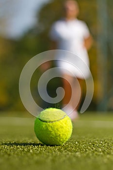 Tennis ball on tennis court with a blurred player