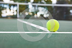 Tennis ball on tennis court with net in background