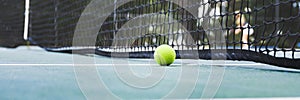 Tennis ball on tennis court with net in background