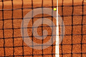Tennis ball on tennis court. View through net