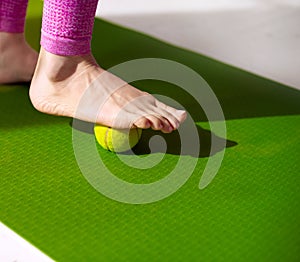 A tennis ball under female foot. Massage for relieve muscle tension, improve circulation, and plantar fasciitis relief.