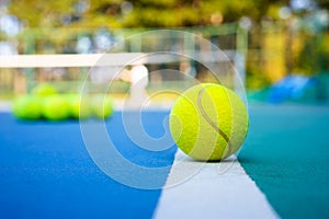 Tennis ball on white Court line on hard modern blue court with Net balls player trees in the background
