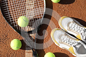 Tennis balls, racket and shoes on clay court, flat lay