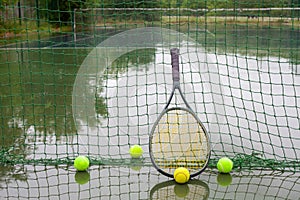 Tennis balls and racket on wet tennis court after raining