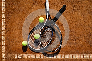 Tennis balls and rackets on clay court, flat lay