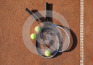 Tennis balls and rackets on clay court, flat lay