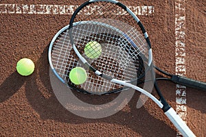 Tennis balls and rackets on clay court, flat lay