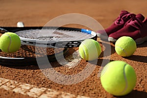 Tennis balls, rackets and shoes on clay court, closeup