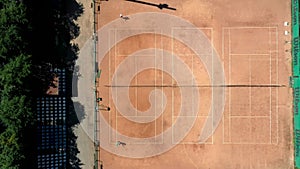Tennis clay court seen from above with two men playing match. They are mature adult, and very agile and healthy. Video