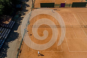 Tennis clay court seen from above with two men playing match. They are mature adult, and very agile and healthy. Video made with