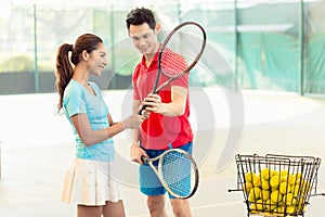 Tennis instructor teaching a beginner player the correct grip