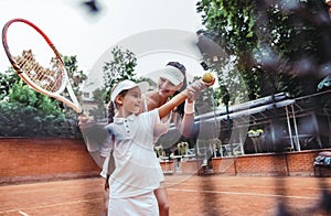 Tennis instructor with young girl on tennis training. Cropped image of a female tennis instructor teaching girl to serve child on