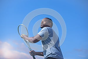 Tennis player with ball and racket against sky background prepares to serve ball