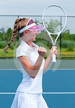 Tennis player celebrating after winning a tennis match. Young woman is playing tennis