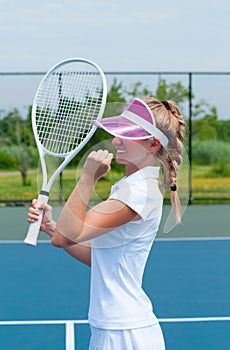 Tennis player celebrating after winning a tennis match. Young woman is playing tennis