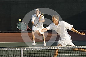 Tennis Player Hitting Ball With Doubles Partner Standing In Background