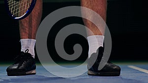 Tennis player holding the ball and getting ready to serve. Close-up feet tennis player preparing to serve. Knocking the